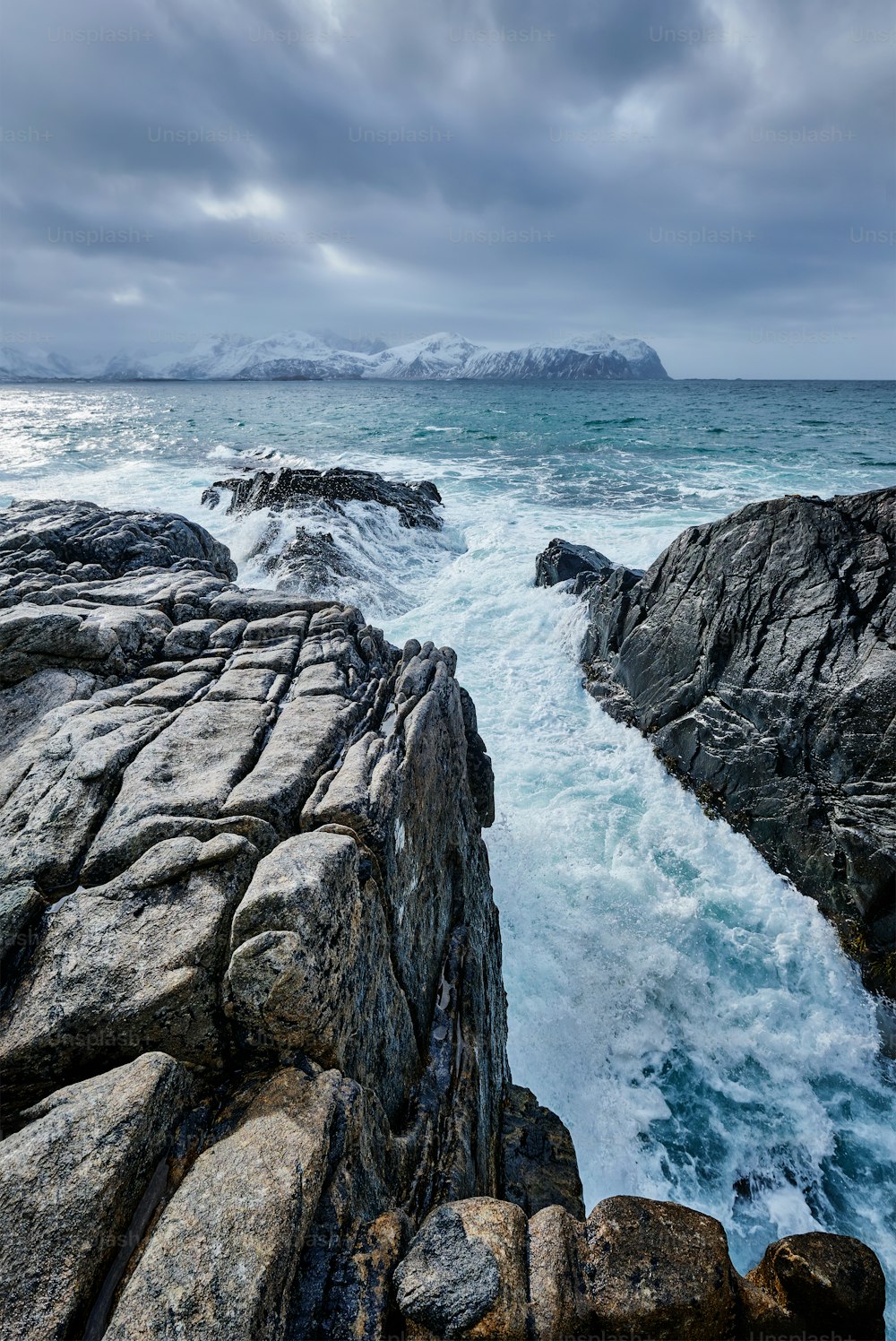 Onde del mare norvegese che si schiacciano sulla costa rocciosa nel fiordo. Vikten, Isole Lofoten, Norvegia
