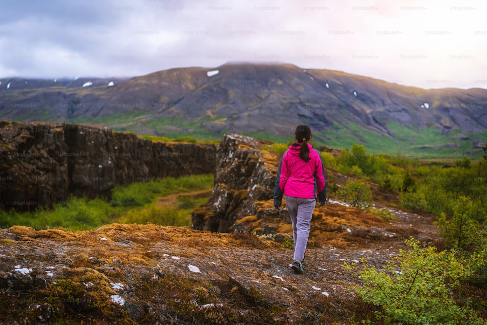 Mujer viajera y exploradora viaja por el paisaje islandés caminando por Islandia para descubrir la naturaleza única en verano.