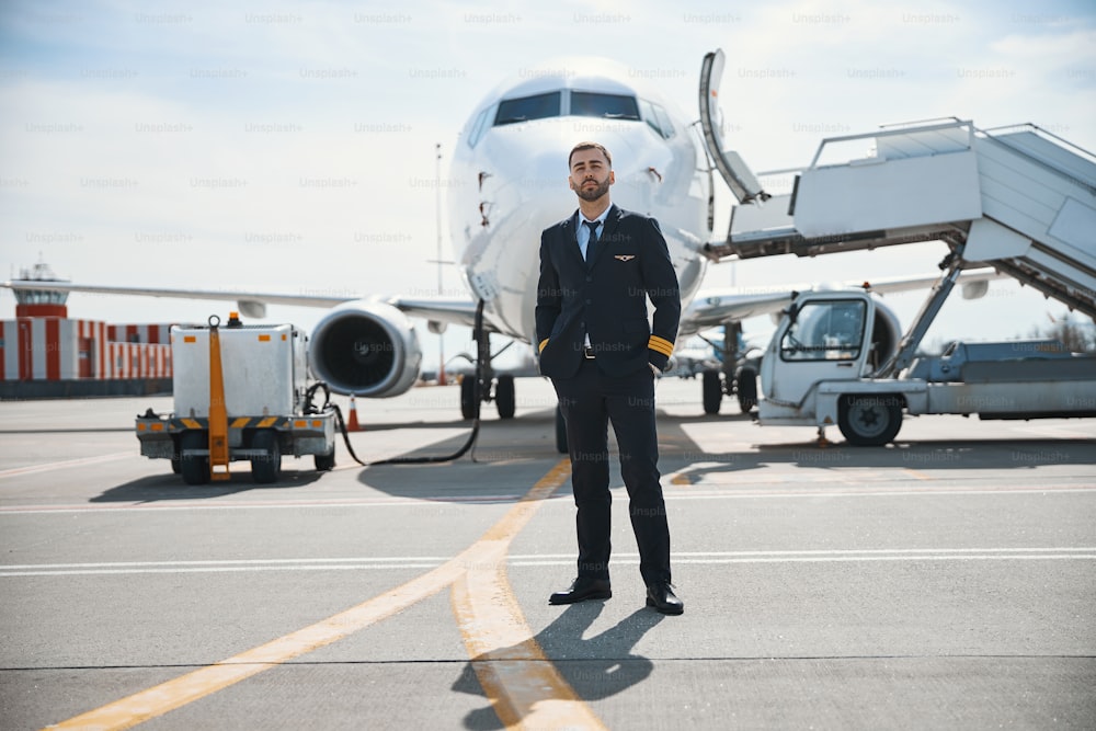 Man pilot looking ahead of himself while waiting for his plane to be ready for takeoff in background
