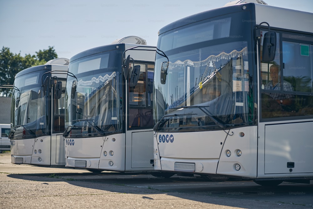 Drei große Autobusse stehen in der Schlange, während sie bereit sind, Passagiere zu transportieren