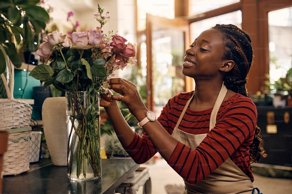 Smiling African American florist making floral arrangement at flower shop.