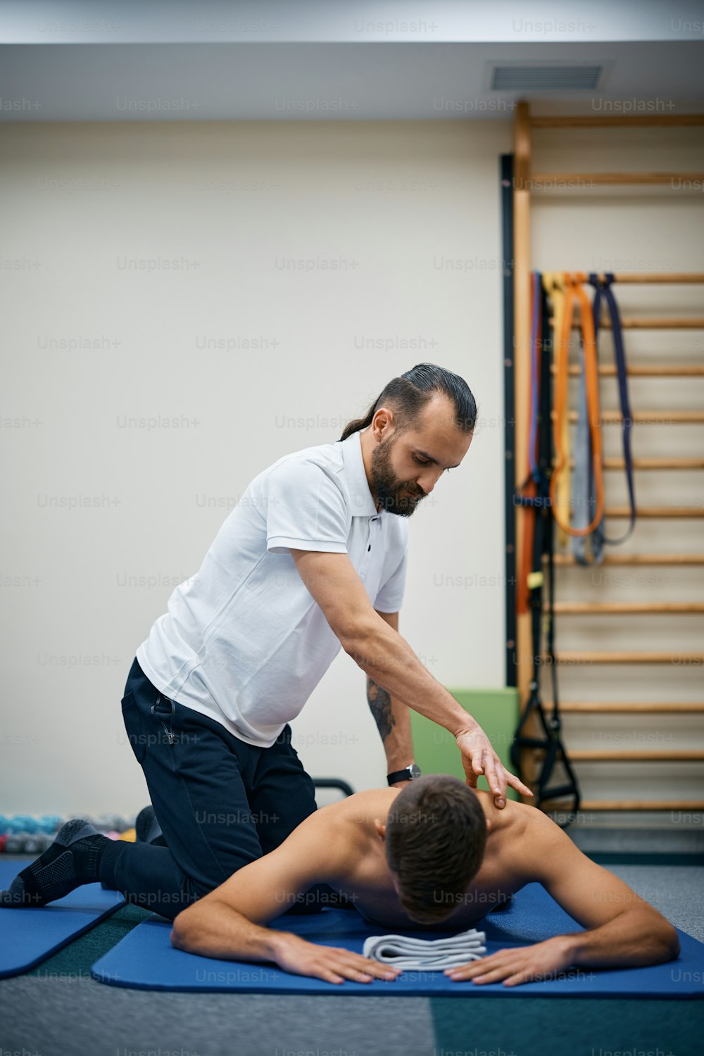 Fisioterapista massaggia la schiena di uno sportivo durante la terapia presso un centro di riabilitazione.