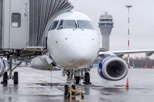 View of the nose and cockpit of the aircraft directly standing on the airport apron. Control ATC tower in the background