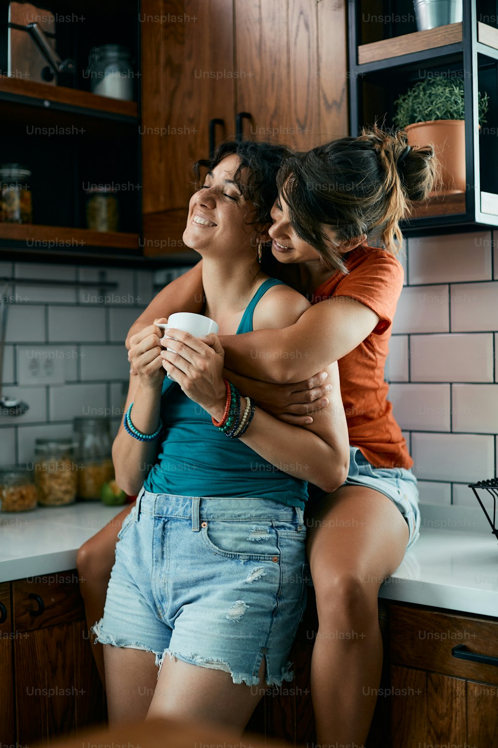 Joven pareja femenina disfrutando de su amor mientras toma café en la cocina.