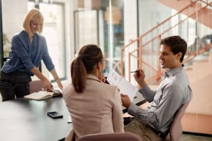 幸せな起業家と彼の女性の同僚は、オフィスで事務処理ビジネス会議を分析しています。