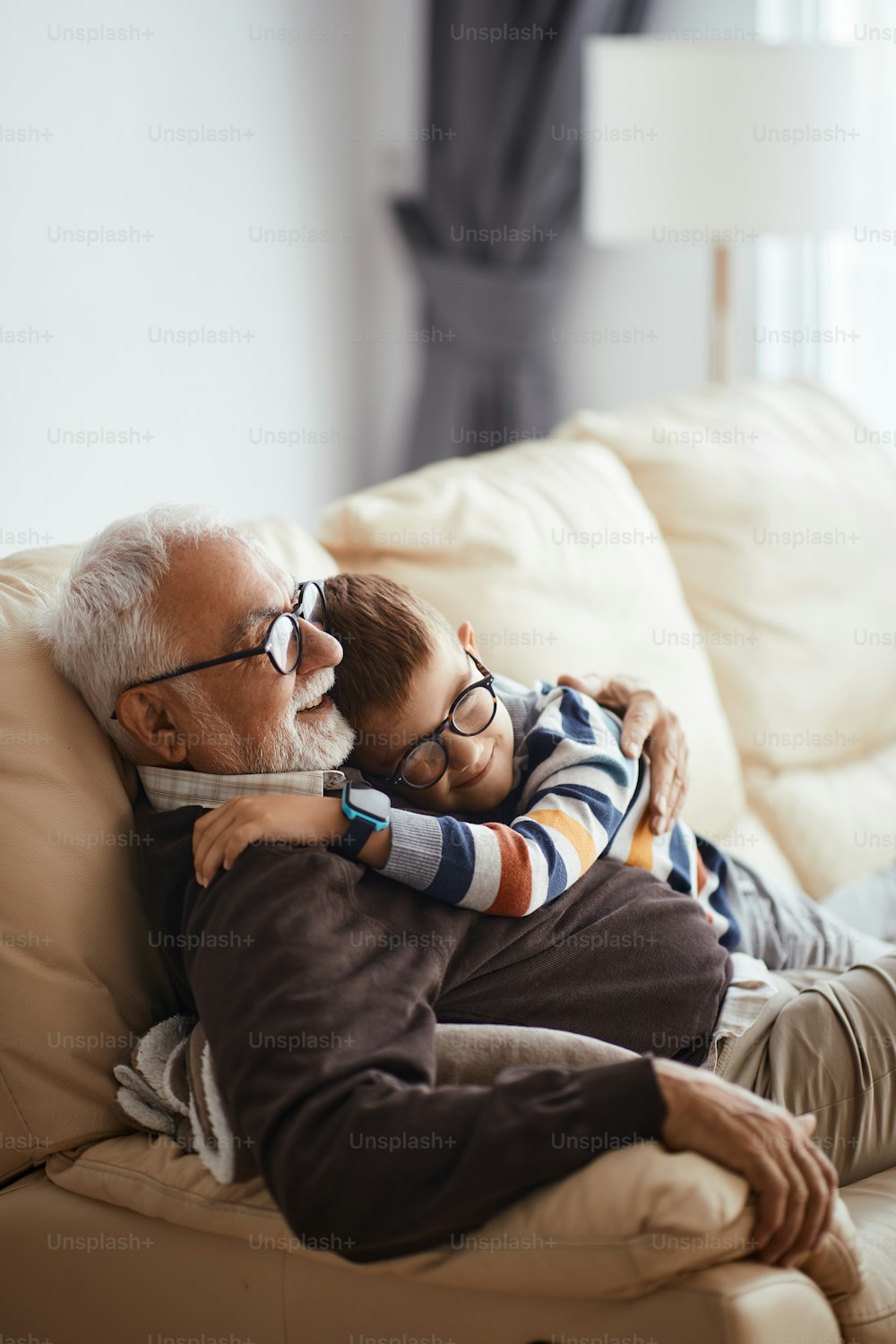 Bambino felice che abbraccia suo nonno mentre trascorre del tempo insieme a casa.