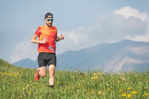 Young sporty man runs through the meadows