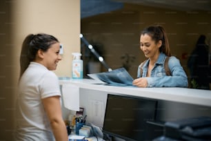 Happy patient examining her X-ray scan at physical therapy reception desk.