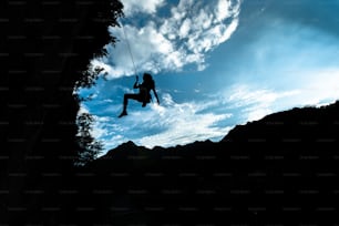 Silhouette of a girl coming down from the rope after climbing.