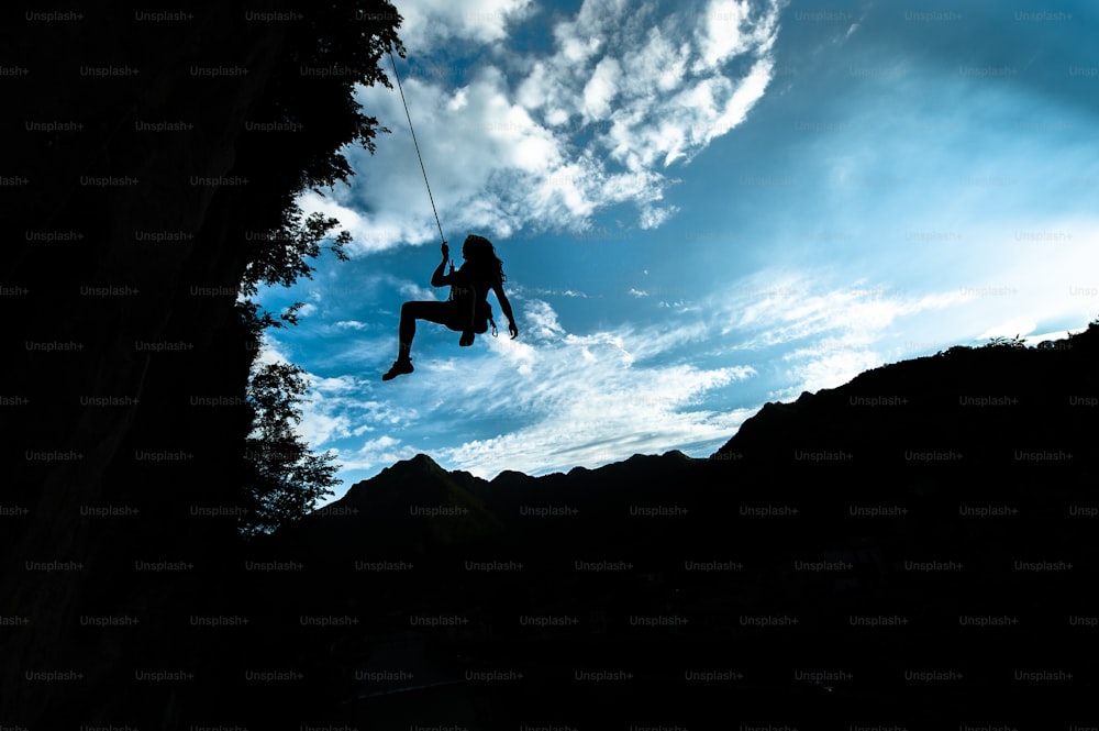 Silhouette of a girl coming down from the rope after climbing.