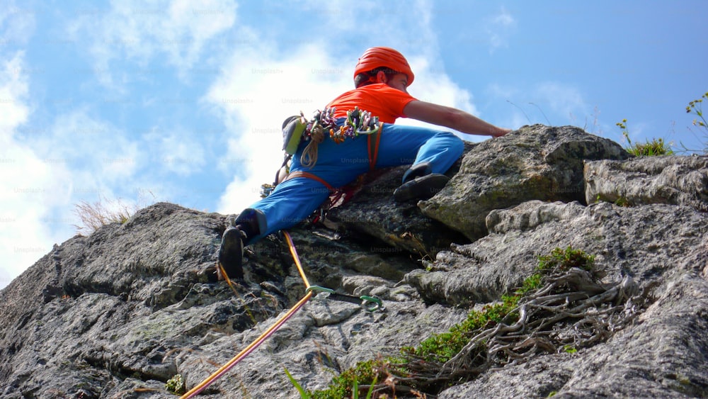 A rock climber dressed in bright colors on a steep granite climbing route in the Alps