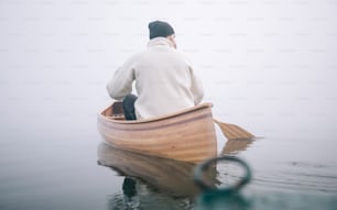 Rear view of man paddling canoe in the winter, copy space.