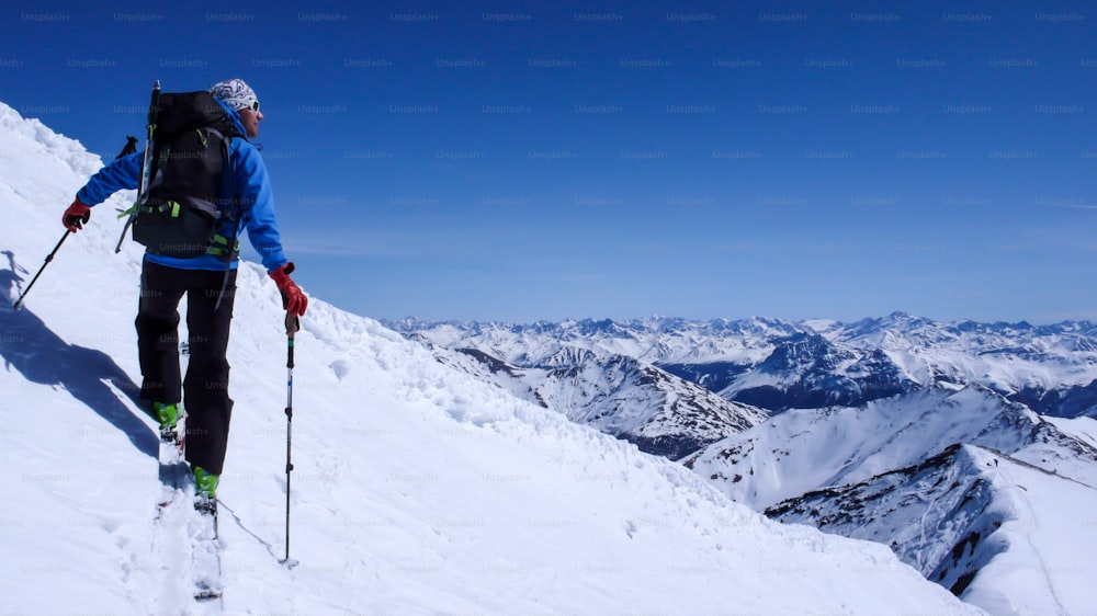 스위스 알프스의 오지에서 눈 슬로프를 올라가는 남성 백컨트리 스키어가 겨울에 스쿠올 근처에서 스키 투어를 하고 있습니다.