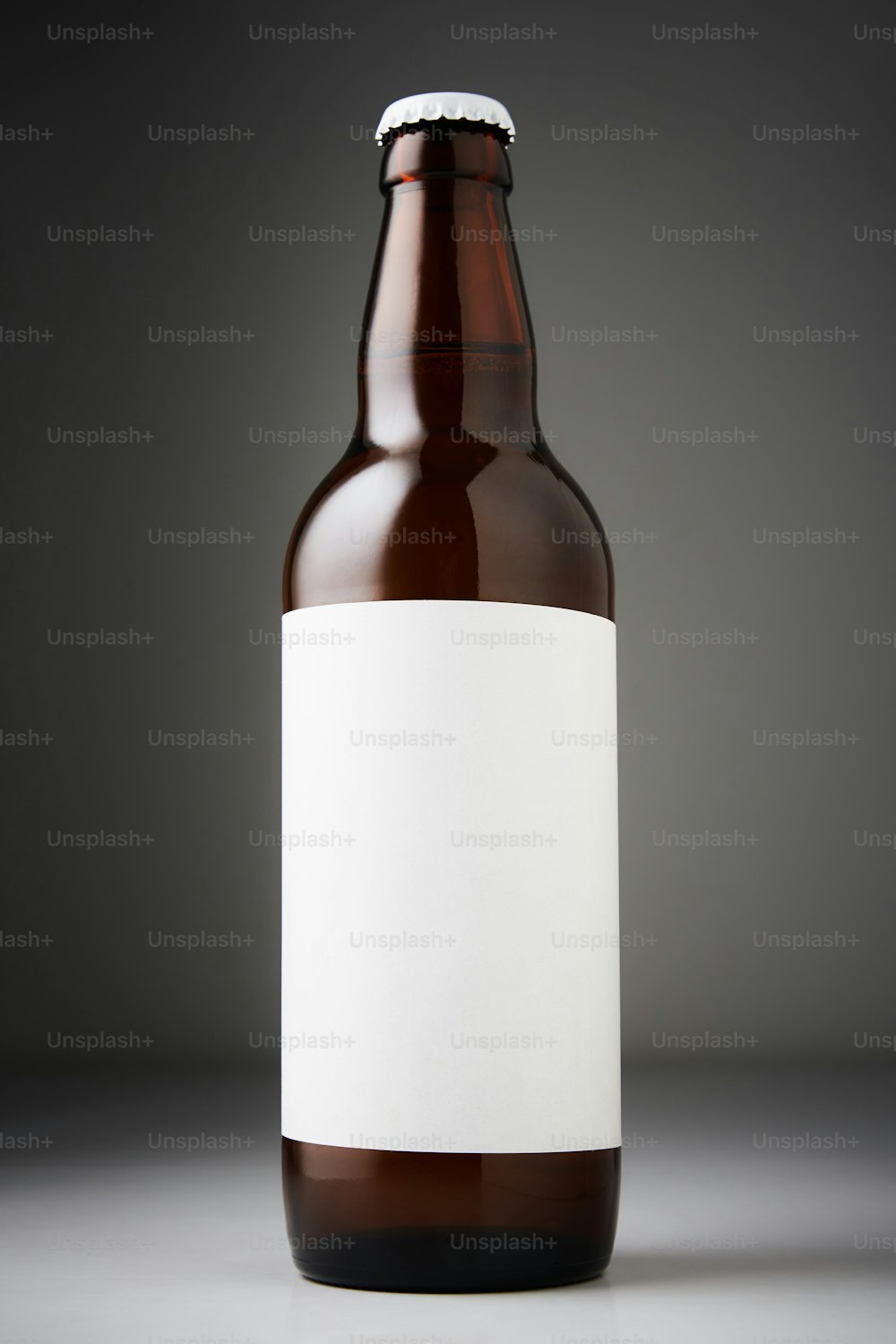 Maqueta de botella de cerveza. Botella llena de cerveza lager con etiquetas en blanco sobre fondo oscuro
