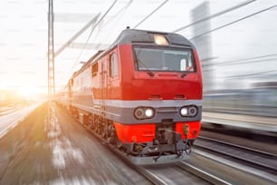 High-speed red passenger train rushing through the railway in the evening at sunset