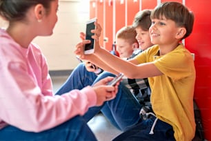 Des écoliers assis par terre et utilisant un smartphone