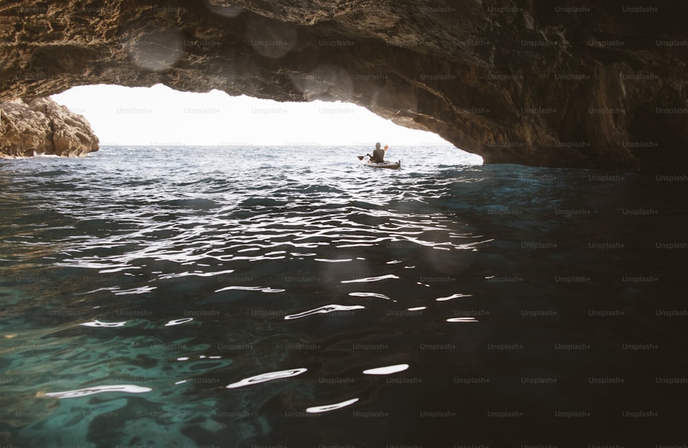 Rear view of man paddling kayak in a cave. Kayaking and spelunking at the same time.
