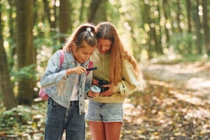 Zwei Mädchen im grünen Wald am Sommertag zusammen.