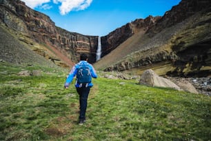 Homem viajante caminhando na paisagem de verão islandesa na cachoeira Hengifoss na Islândia. A cachoeira está situada na parte oriental da Islândia.