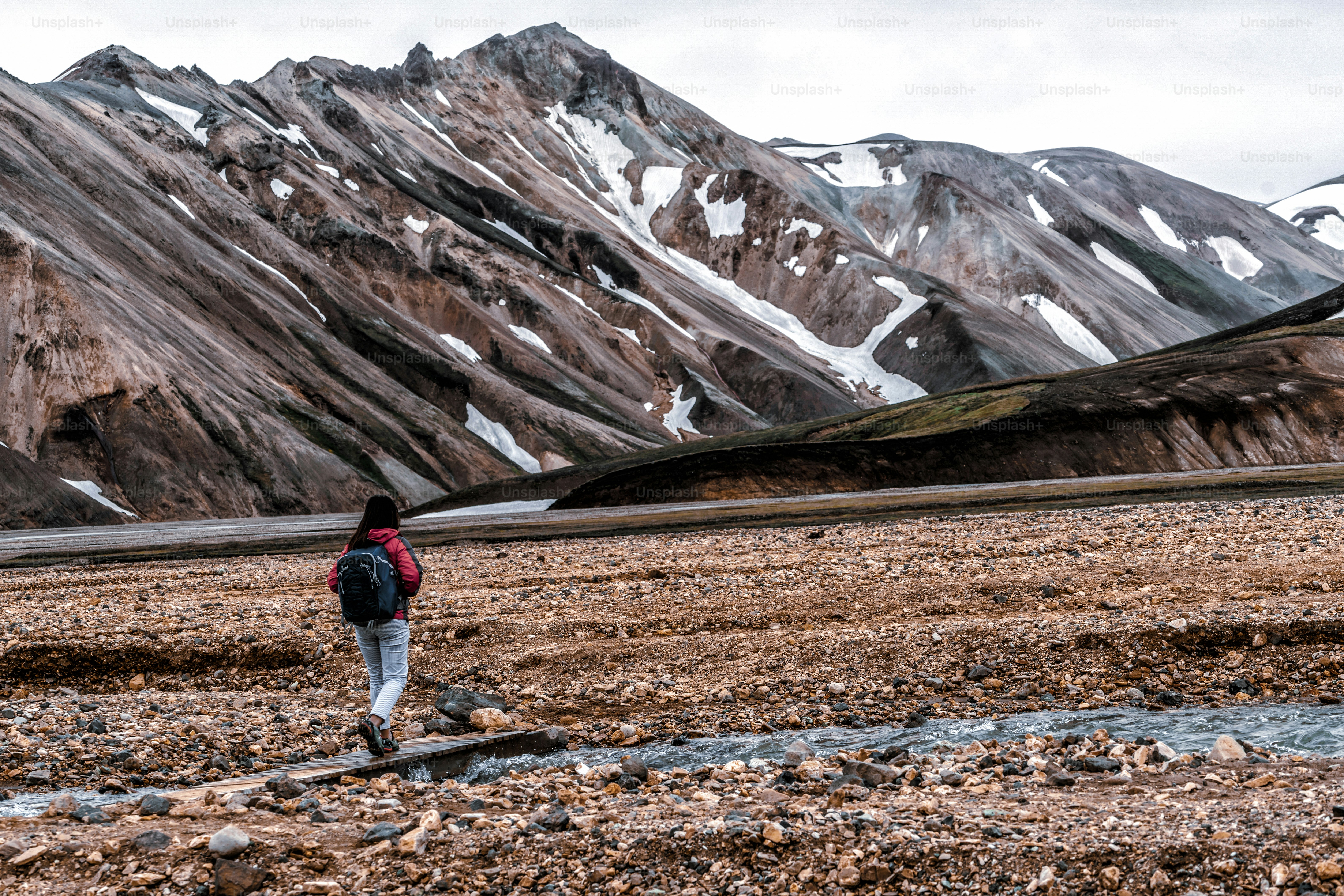 Traveler hiking at Landmannalaugar surreal nature landscape in highland of Iceland, Nordic, Europe. Beautiful colorful snow mountain terrain famous for summer trekking adventure and outdoor walking.