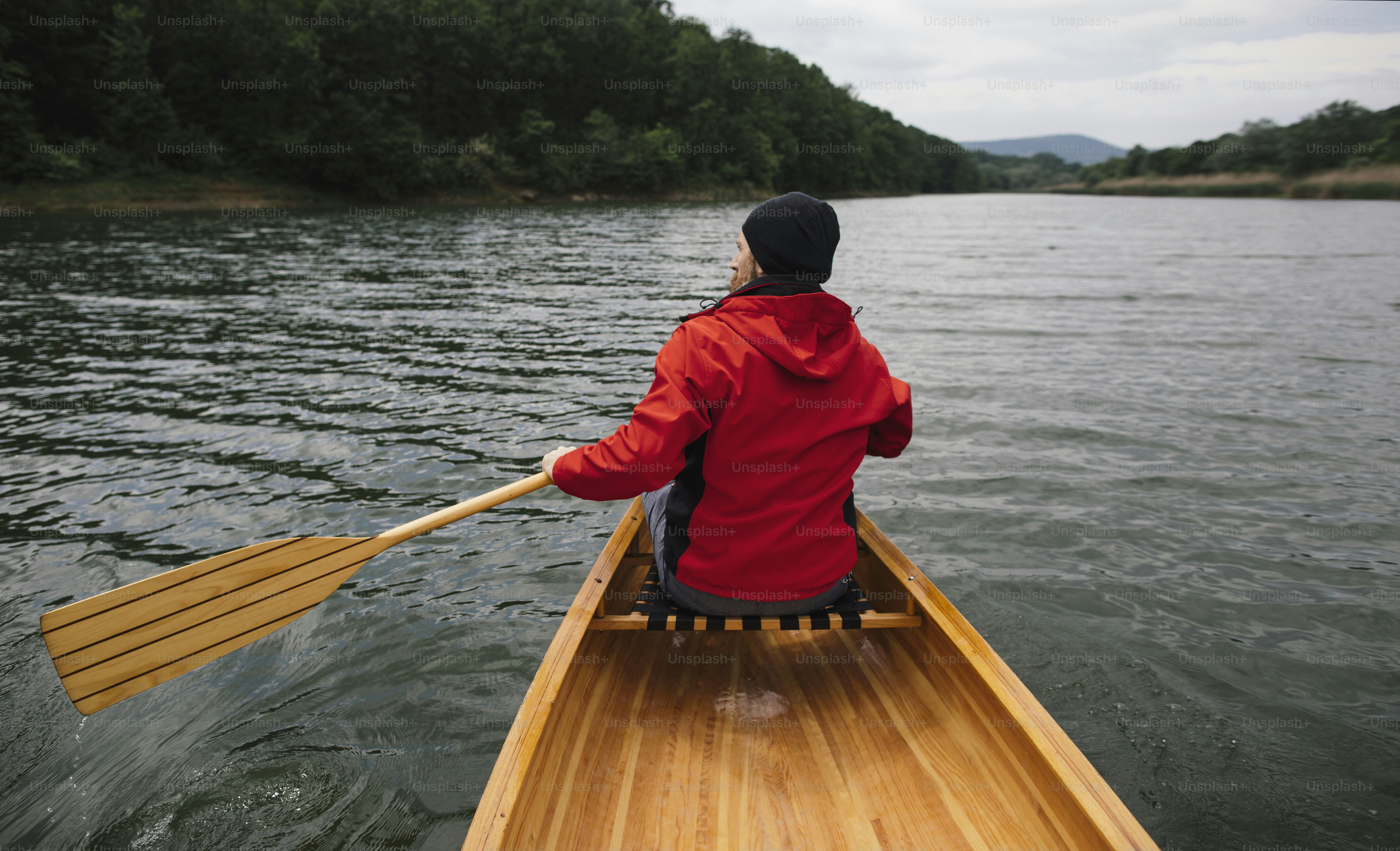 Rear view of man paddling canoe on the lake. Rainy day boat ride. photo
