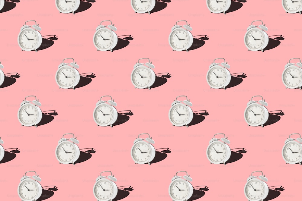 ピンクの背景にビンテージの目覚まし時計。白いレトロな目覚まし時計とシームレスなパターン。ミニマルなスタイル