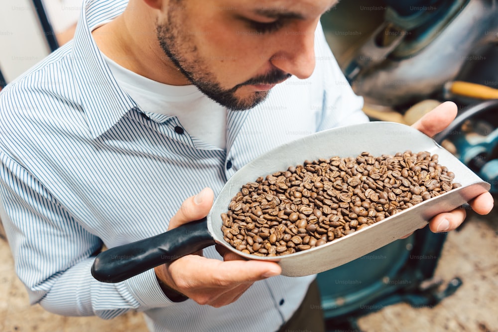 Homme dans la torréfaction de café avec des grains frais dans une petite pelle