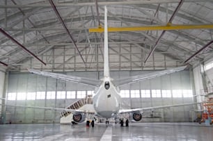 Aerei passeggeri per la manutenzione della riparazione del motore e della fusoliera nell'hangar aeroportuale. Vista posteriore della coda