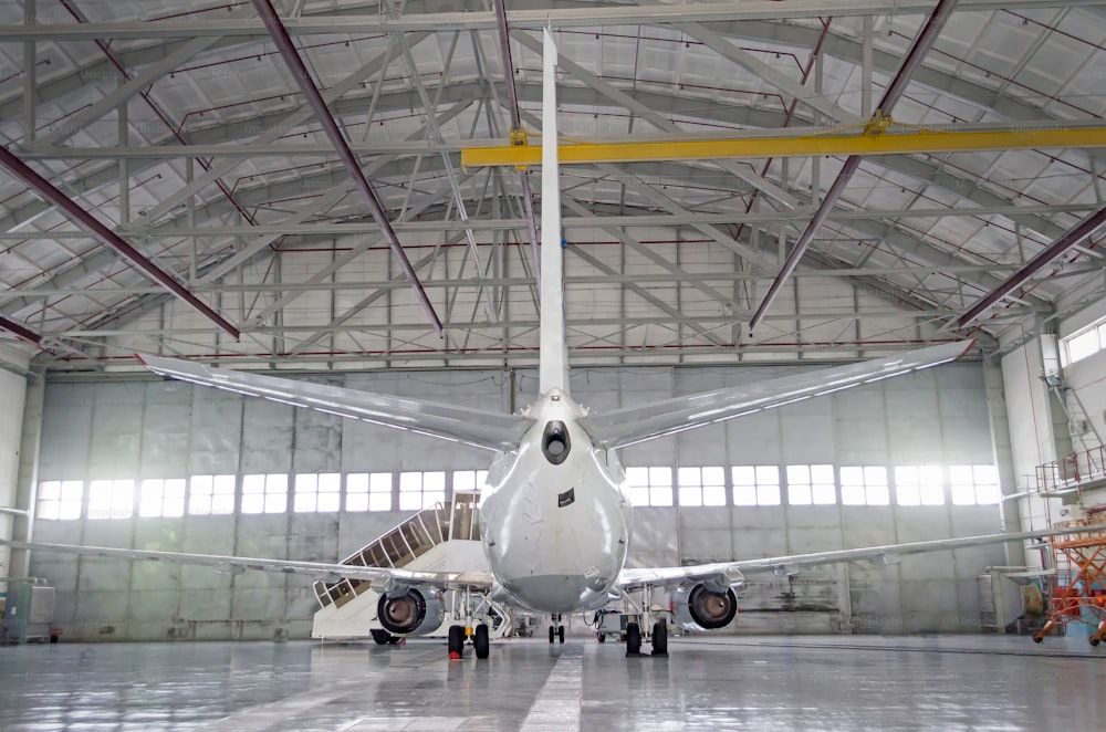 Aerei passeggeri per la manutenzione della riparazione del motore e della fusoliera nell'hangar aeroportuale. Vista posteriore della coda