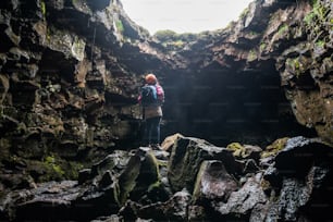 Donna viaggiatrice esplora il tunnel di lava in Islanda. Raufarholshellir è un bellissimo mondo nascosto di grotte. È uno dei tubi di lava più lunghi e conosciuti in Islanda, in Europa, per le sue incredibili avventure.