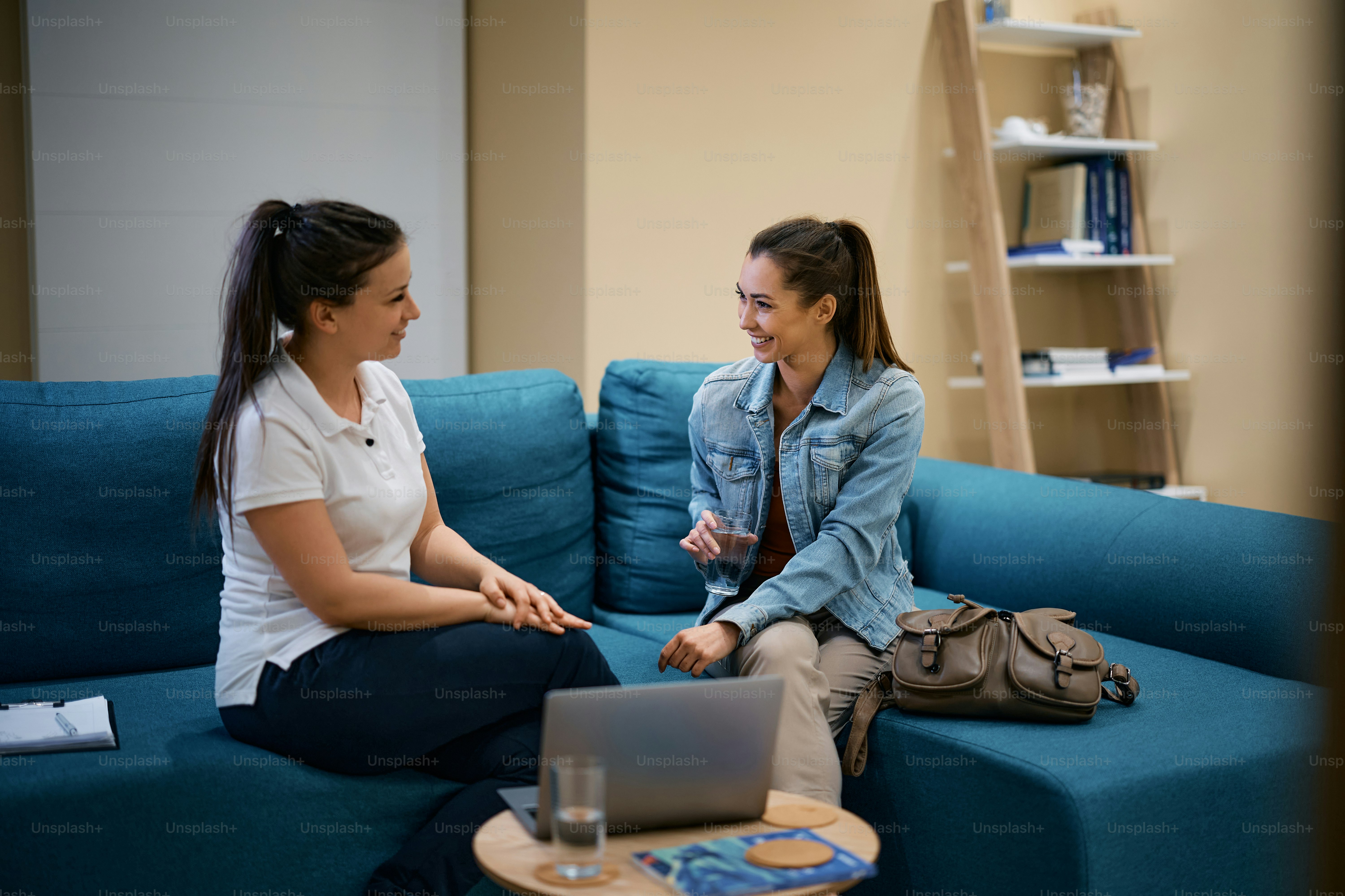 Young happy woman communicating with physiotherapist while having a glass of water at physical therapy center.