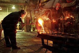 Steel workers melting iron in furnace steel mill