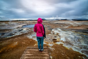 Mulher viajante viaja para Hverir na Islândia. Hverir (em islandês: Hverarond) é uma área geotérmica em Myvatn. É um destino famoso perto do Lago Myvatn, Krafla região nordeste da Islândia, Europa.