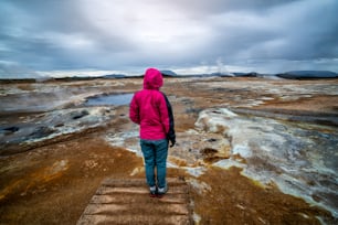 Woman traveler travels to Hverir in Iceland. Hverir (Icelandic: Hverarond) is geothermal area in Myvatn. It is a famous destination near Lake Myvatn, Krafla northeastern region of Iceland, Europe.