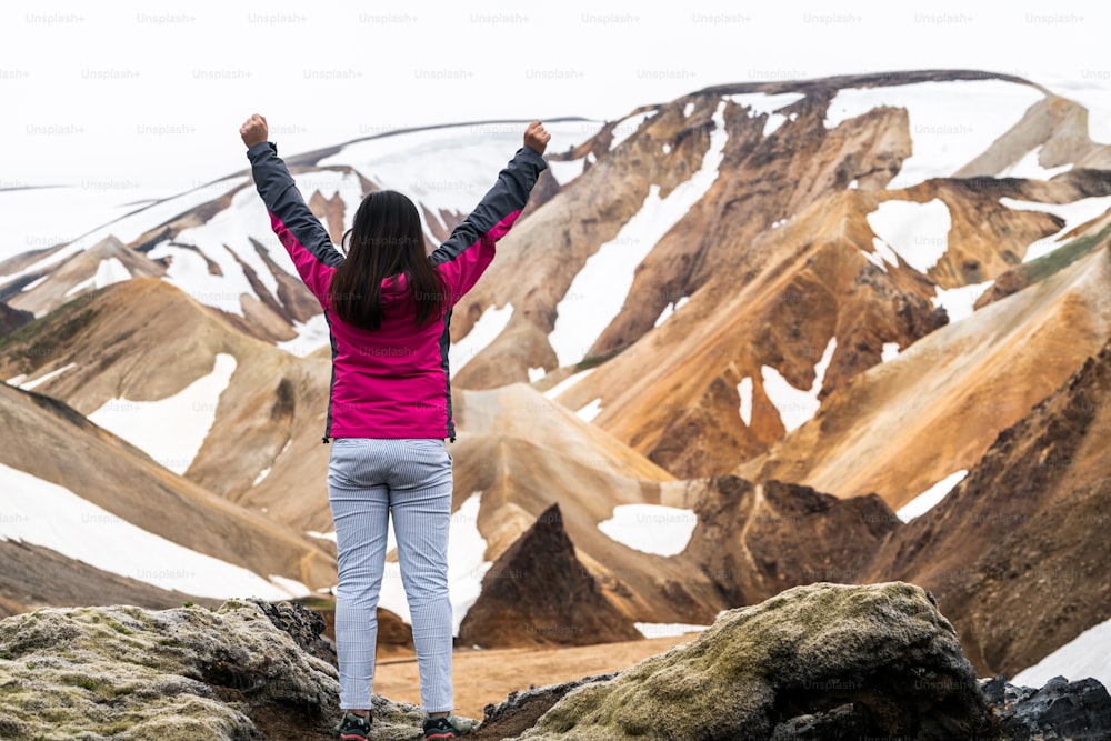 Traveler hiking at Landmannalaugar surreal nature landscape in highland of Iceland, Nordic, Europe. Beautiful colorful snow mountain terrain famous for summer trekking adventure and outdoor walking.