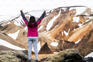 Traveler hiking at Landmannalaugar surreal nature landscape in highland of Iceland, Nordic, Europe. Beautiful colorful snow mountain terrain famous for summer trekking adventure and outdoor walking.