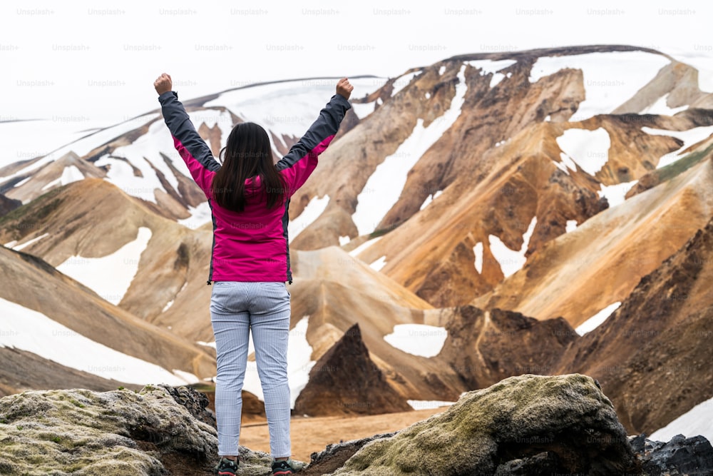 Viaggiatore che fa un'escursione al paesaggio surreale della natura di Landmannalaugar nell'altopiano dell'Islanda, nordico, Europa. Splendido terreno di montagna innevato colorato famoso per l'avventura di trekking estivo e le passeggiate all'aperto.