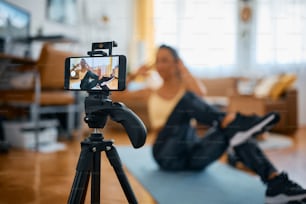 Close-up of athletic woman vlogging while practicing sit-ups at home.