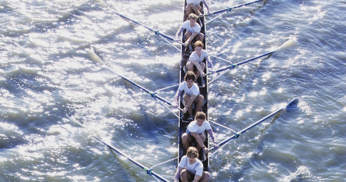 A group of people rowing a long boat in the water photo – Rowing Image ...