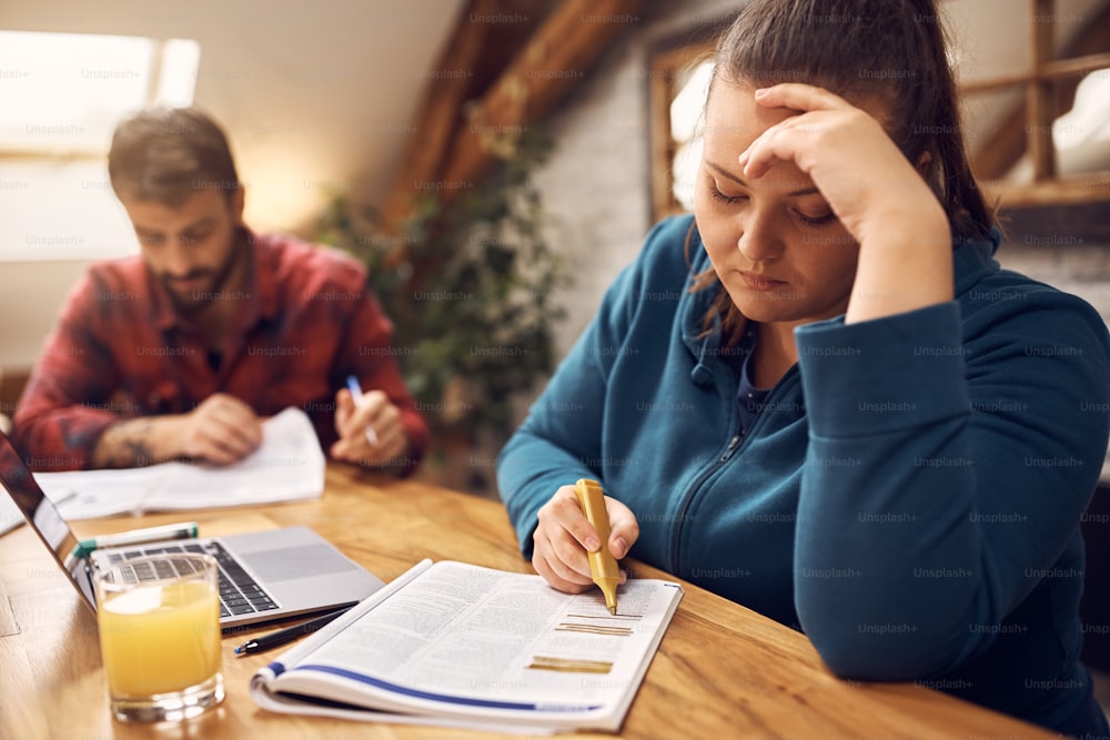 Jeune femme étudiant pour les examens à venir avec son ami masculin à la maison.