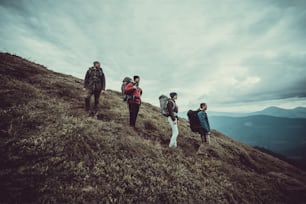 Les quatre personnes avec des sacs à dos debout sur la montagne