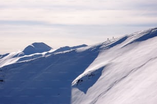 two backcountry skiers hiking up on a long mountain ridge towards the summit near Klosters in the Swiss Alps in deep winter
