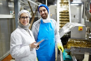 Travailleurs réussis d’une usine de production de fruits de mer en uniforme regardant la caméra au travail