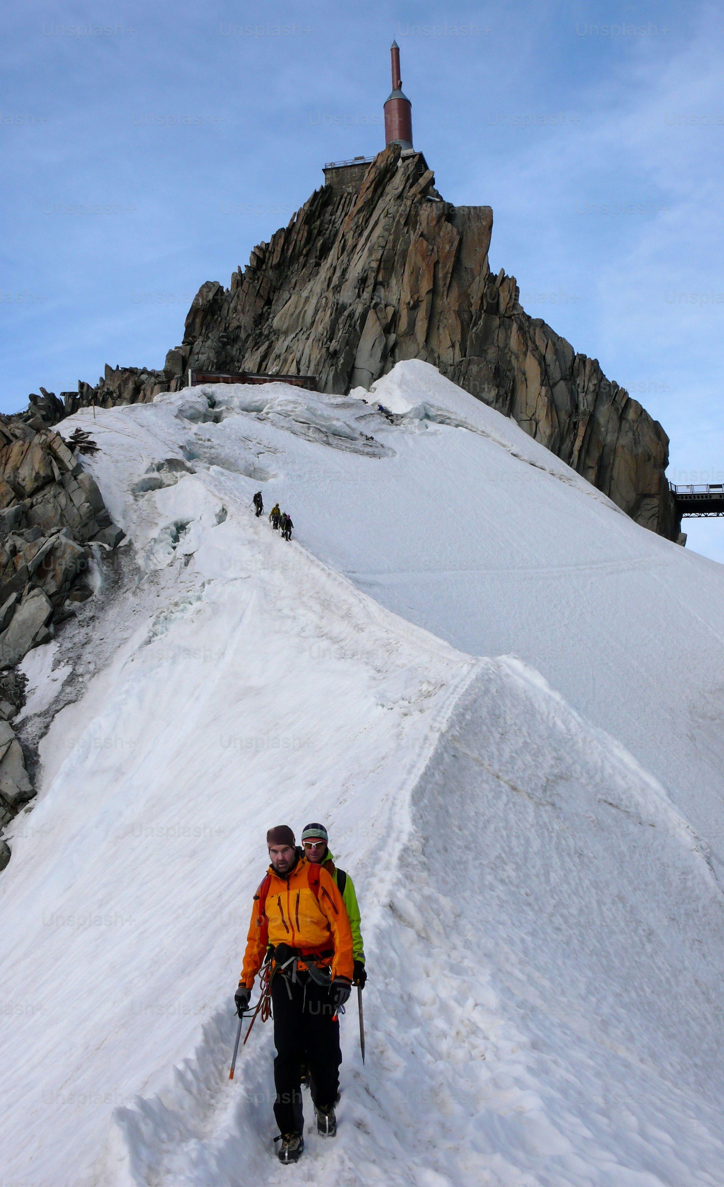 mountain guide and a male client on a snow ridge heading down from a high summit in the French Alps near Chamonix on a beautiful summer day