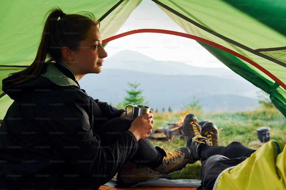 Man and woman inside of tent together. Majestic Carpathian Mountains. Beautiful landscape of untouched nature.
