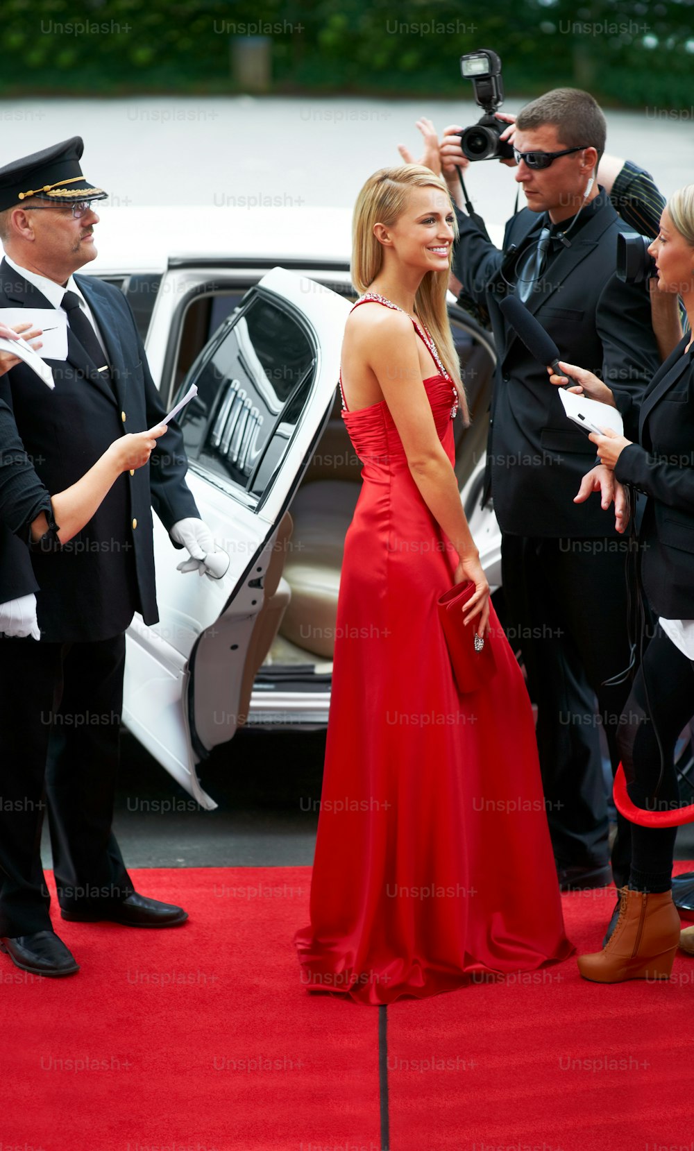 車の前に立つ赤いドレスを着た女性