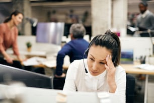 Asian female entrepreneur feeling worried while working on desktop PC and reading an e-mail at corporate office.