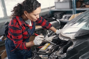 Young master examining car motor while working at service station