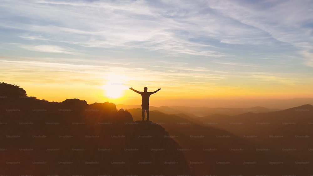 The man standing on the mountain on the picturesque sunset background