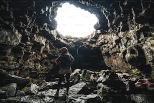 Donna viaggiatrice esplora il tunnel di lava in Islanda. Raufarholshellir è un bellissimo mondo nascosto di grotte. È uno dei tubi di lava più lunghi e conosciuti in Islanda, in Europa, per le sue incredibili avventure.